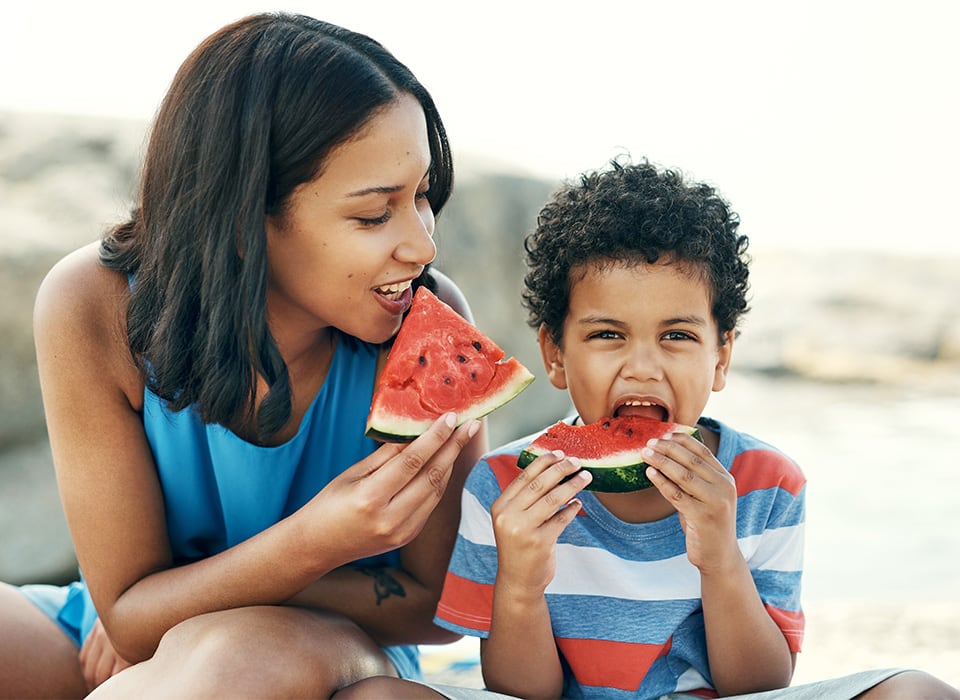 mother and son eating watermelon outside