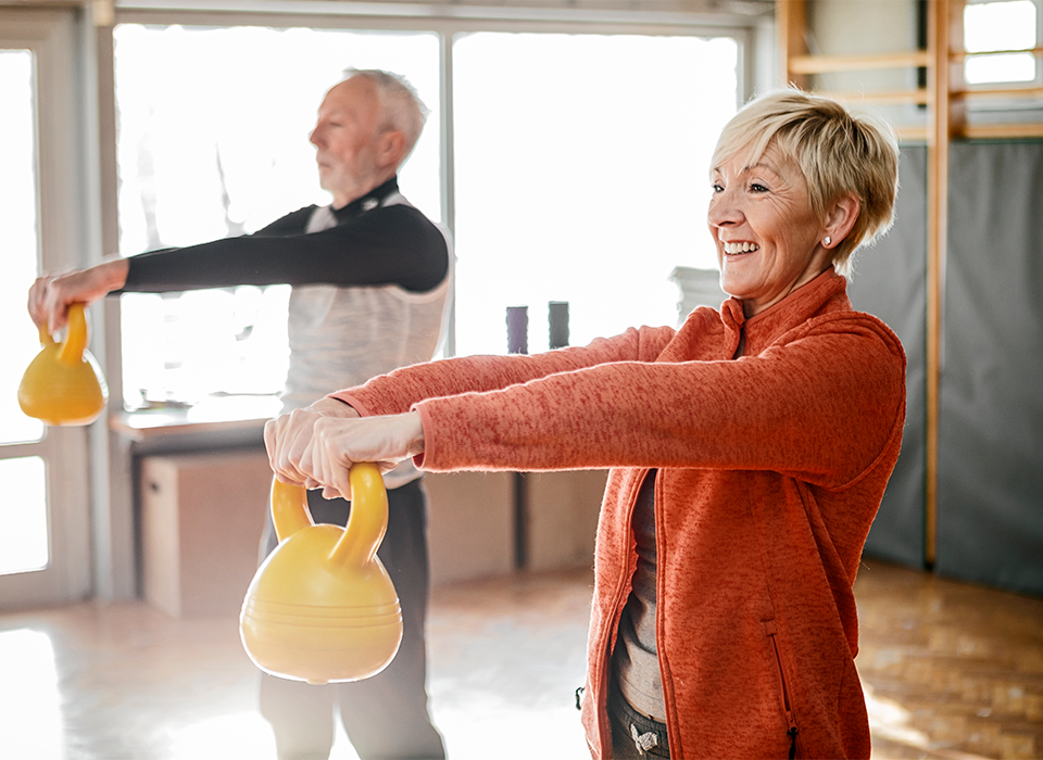two older people holding kettlebells in an exercise class
