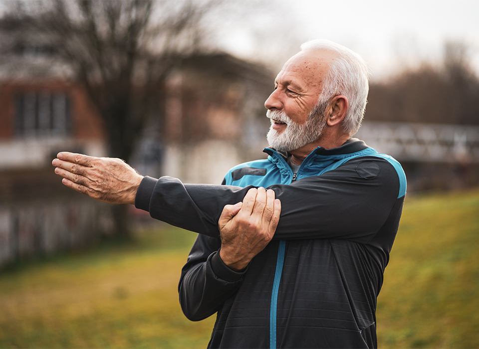 man stretches his arm while outside