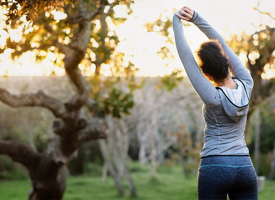 a woman in athletic clothing stretches outside