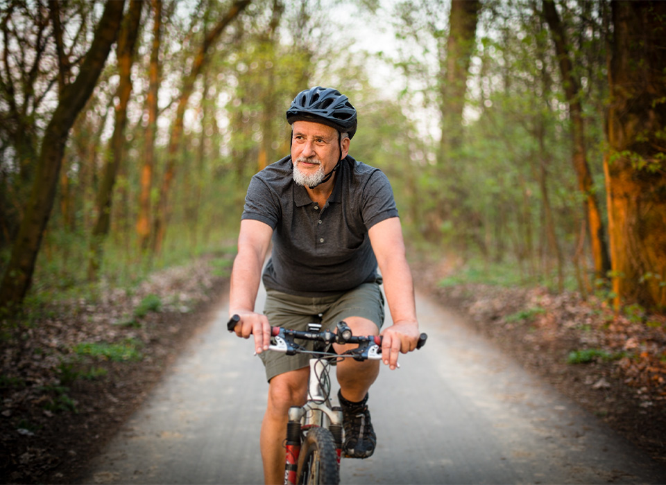 man with helmet biking through wooded bike path