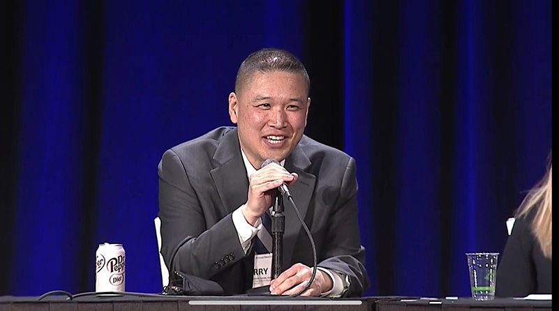 Dr. Garry Ho talking into a microphone on a panel