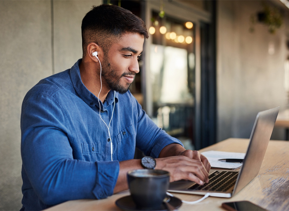 man on his laptop and headphones in a coffee shop