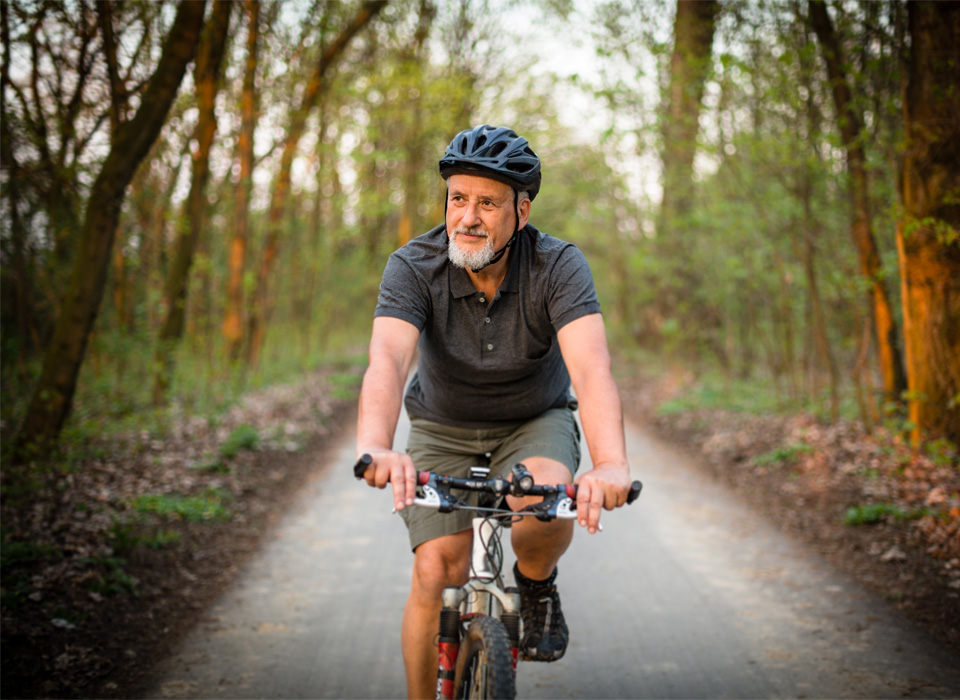a man wearing a helmet bikes along a wooded bike trail