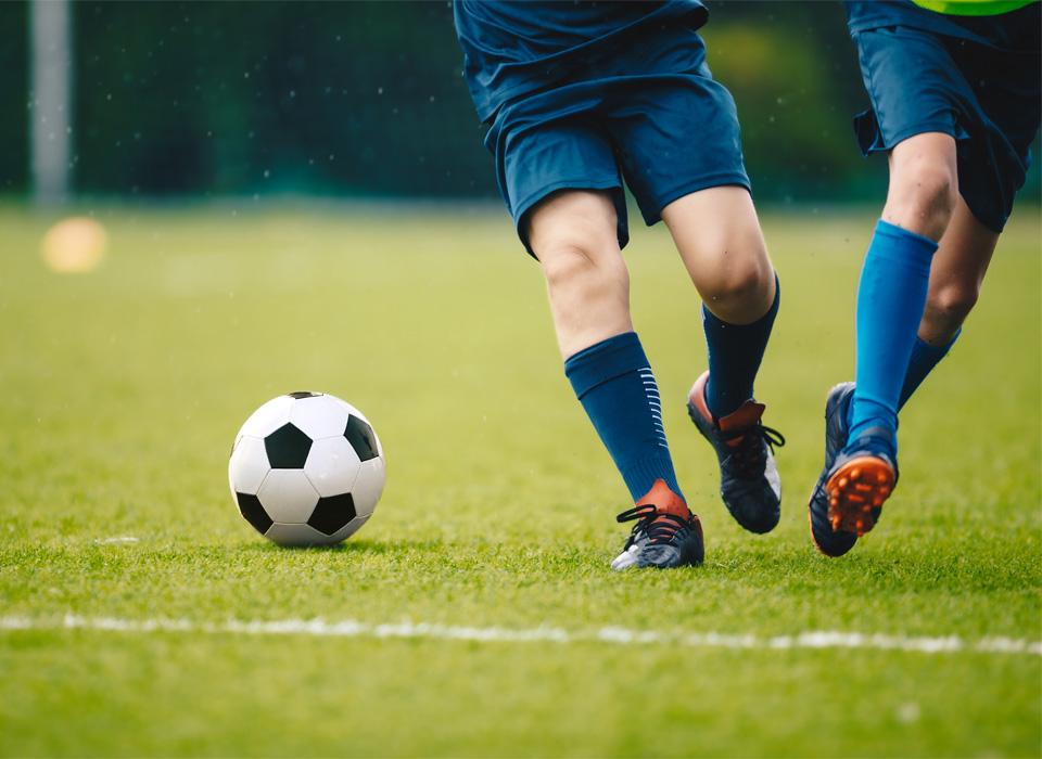 a close up of the feet and legs of two soccer players trying to kick a soccer ball