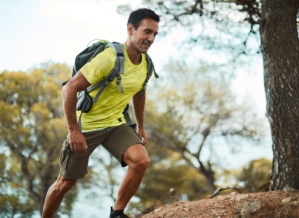 a man in a hiking backpack walks up a steep hill or mountain