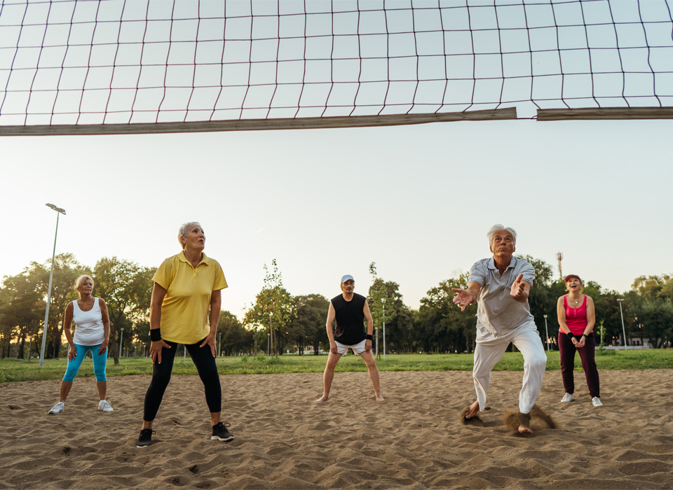 older volleyball players on a sand court in a park
