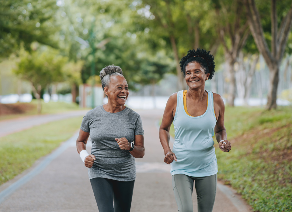 two older women in exercise clothes powerwalk on a park path
