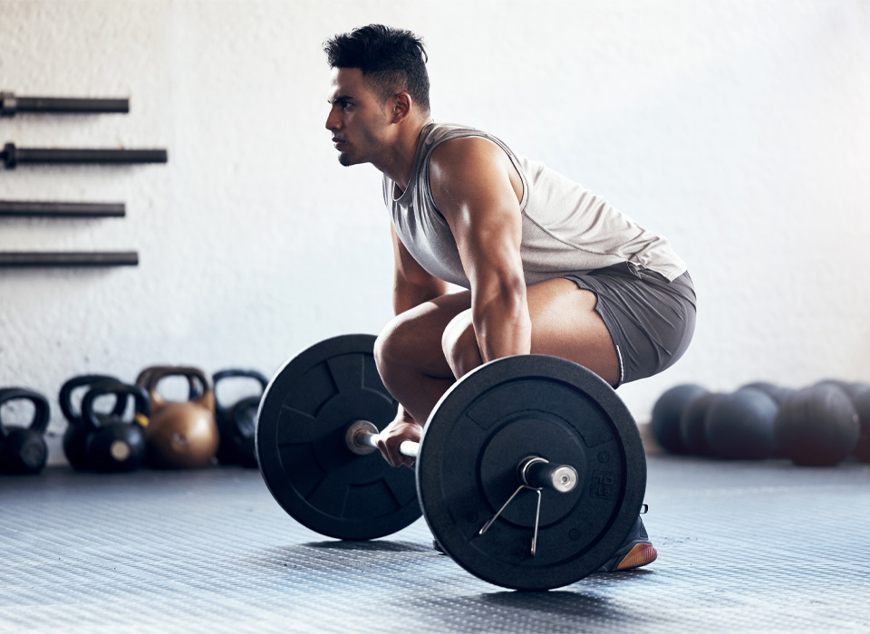 a man bending down to pick up a barbell