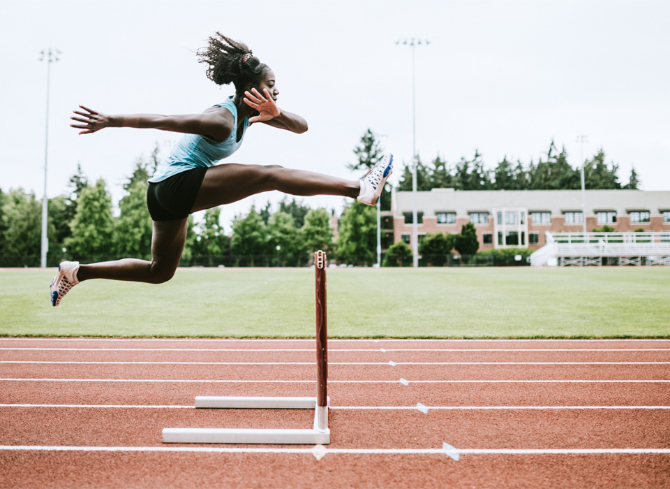 a woman goes over a hurdle