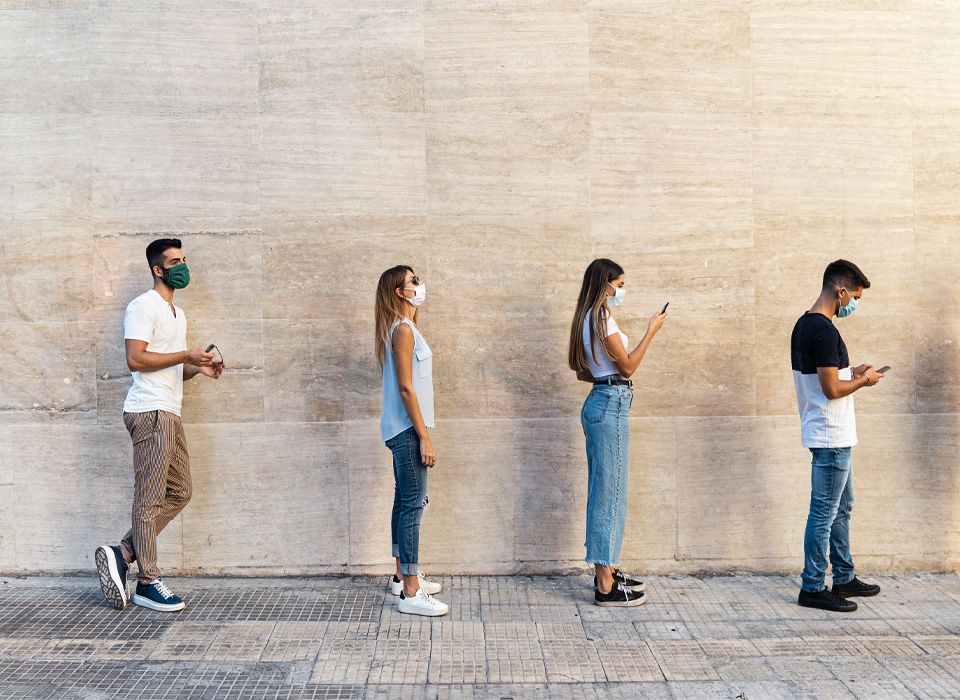 Four people in masks stand six feet apart in an outdoor line