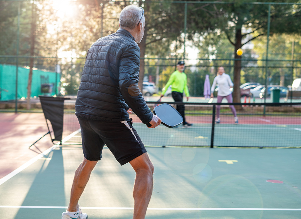 man playing pickleball outside, ready for the serve coming toward him