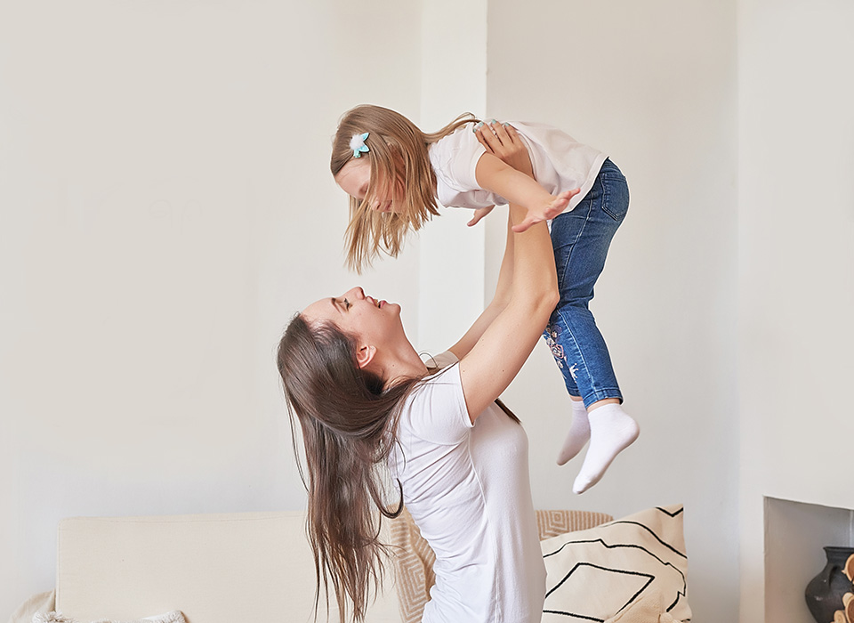 woman holding young child above her head, both smiling
