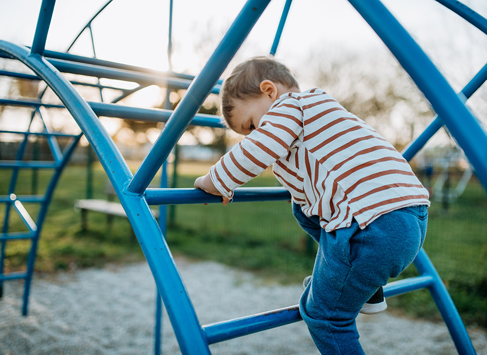 young child climbing on blue playground equipment