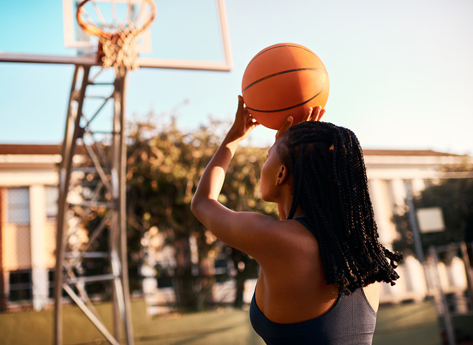 a young woman about to shoot a basketball at an outdoor hoop